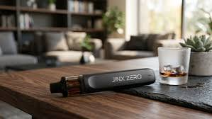 Sleek matte black JINX ZERO nicotine free pod vape device on a modern wooden coffee table next to an iced drink -VapeFeat device review