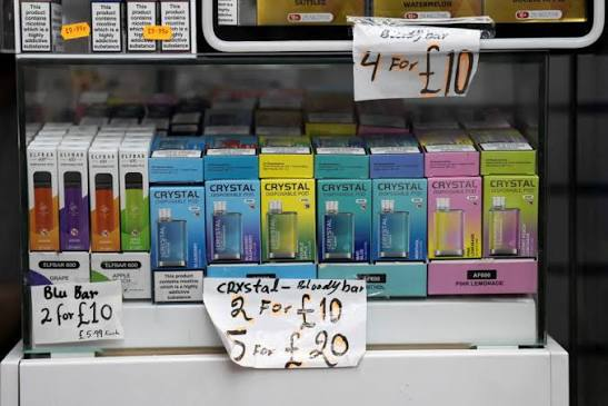 Retail glass counter display shelf loaded with packaged disposable vapes including SKE Crystal Bar and Elf Bar 600 with multi-buy discount price signs - Vape Shop Retail Buying Guide on VapeFeat